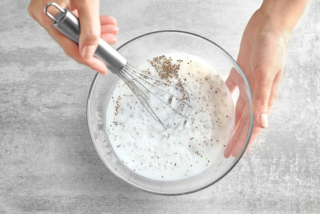 Whisking chia seeds into milk in a glass bowl to start the chia pudding snack recipe