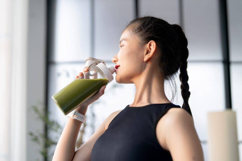 Woman drinking chlorella benefits smoothie after workout