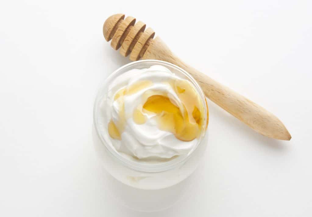 Greek yogurt with honey in glass bowl on white background