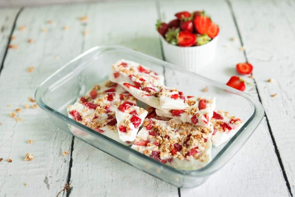 Frozen Greek yogurt bark with berries and nuts stacked on table