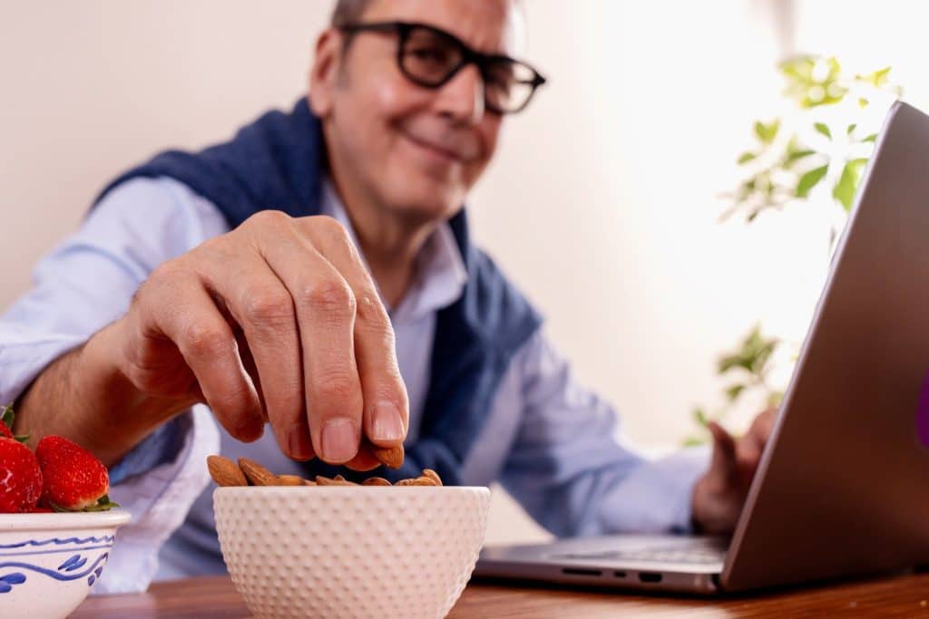 Elderly businessman  taking almonds as a portioned healthy office snack