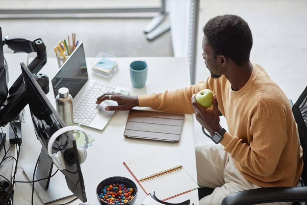 Professional enjoying an apple while working as healthy office snacks