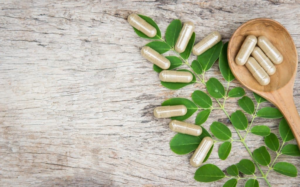 Moringa capsules on leaves showing moringa benefits