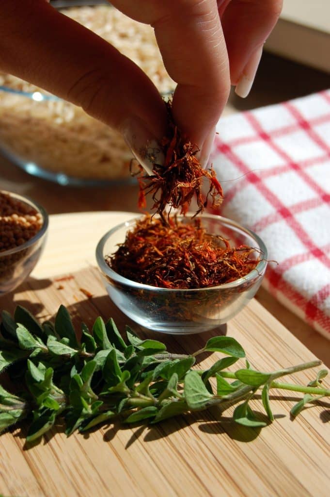 Hand sprinkling saffron threads into a bowl