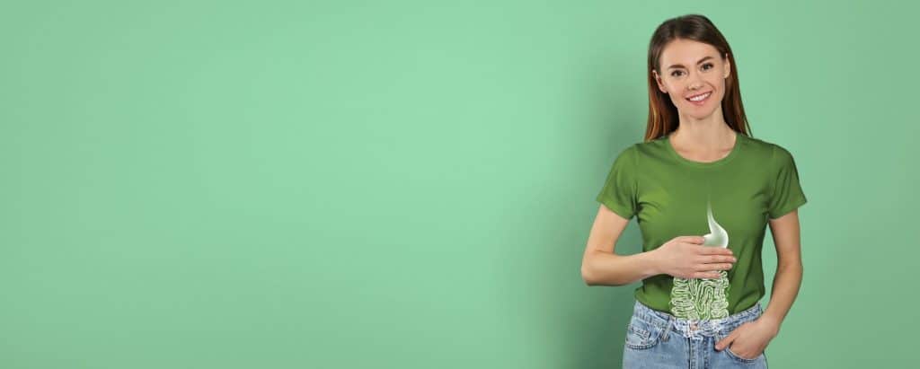 Young woman with a stomach illustration on her shirt, symbolizing strong digestion and balanced gut health.