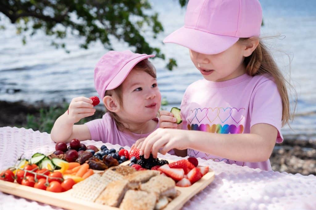 Kids enjoying a colorful fruit platter with berries and watermelon, showing natural fruits for energy at a family picnic.