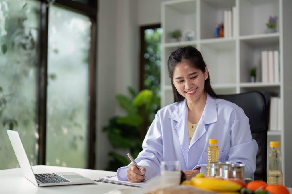 Nutritionist writing notes after looking at food labels at a desk with fresh fruits and vegetables, highlighting the science behind the future of clean eating.