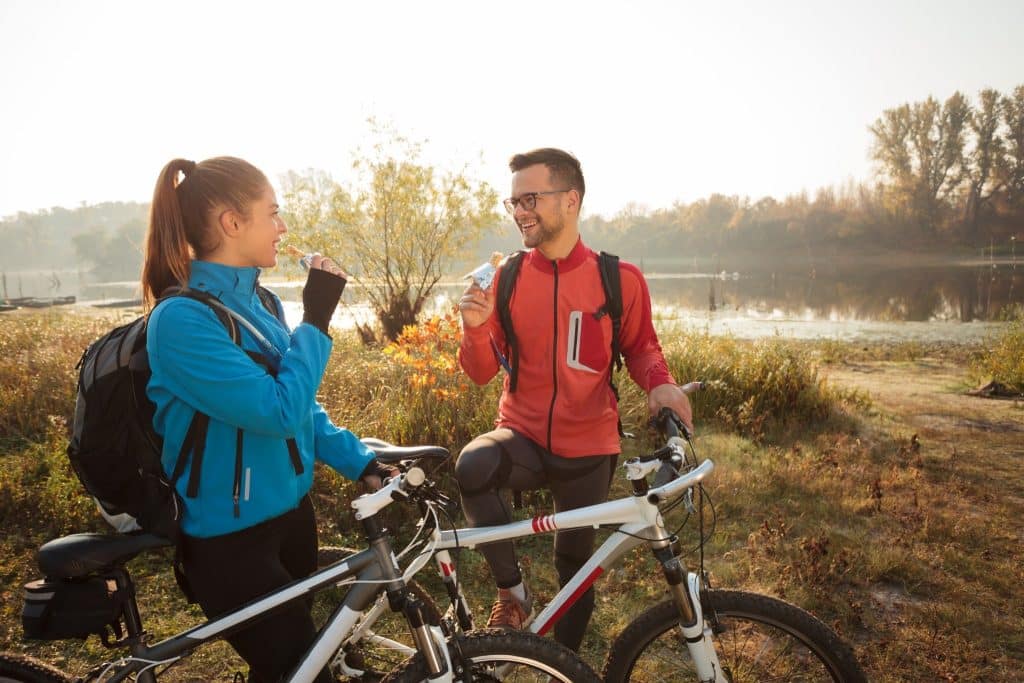 Cyclists taking a break and eating homemade energy bars during outdoor ride.