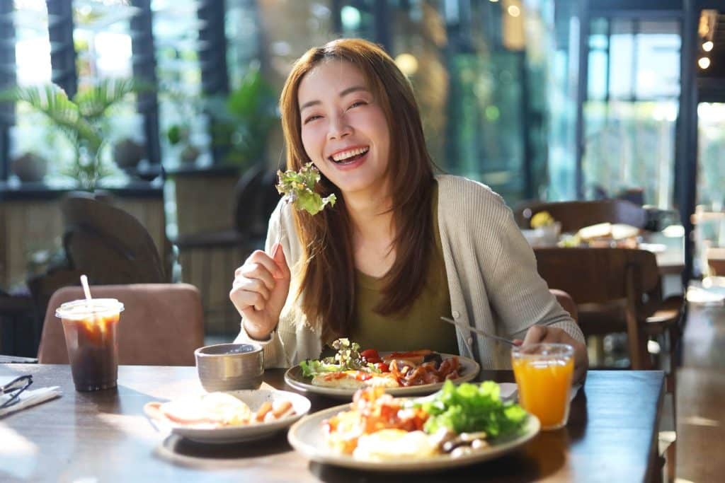 Smiling woman enjoying a healthy meal that supports gut microbiome and prebiotics for gut health