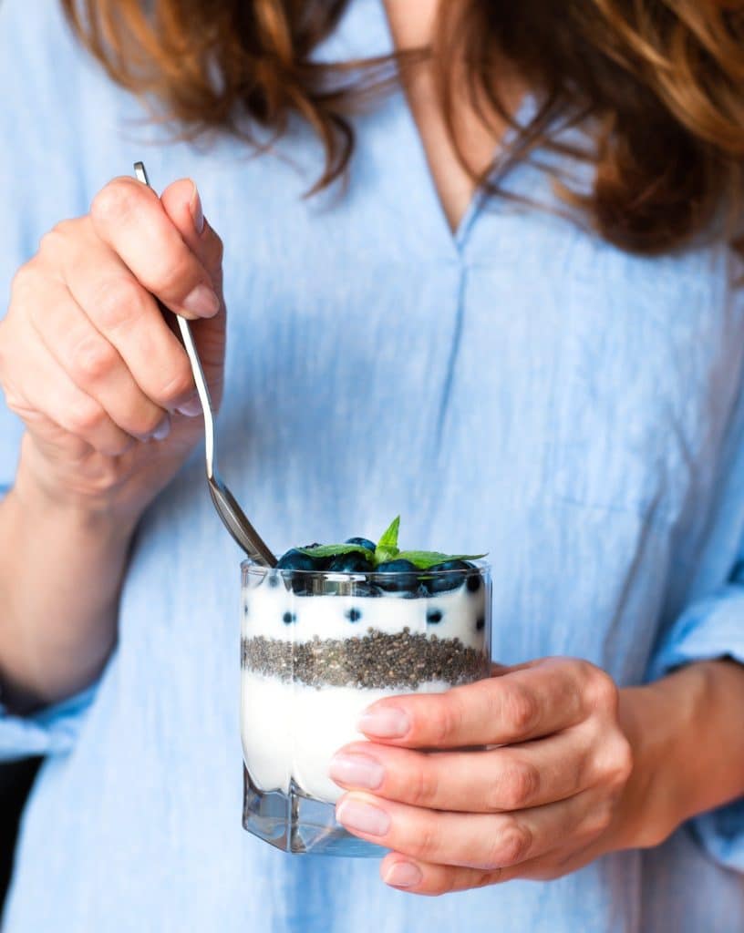 Woman holding a yogurt parfait with chia seeds and blueberries