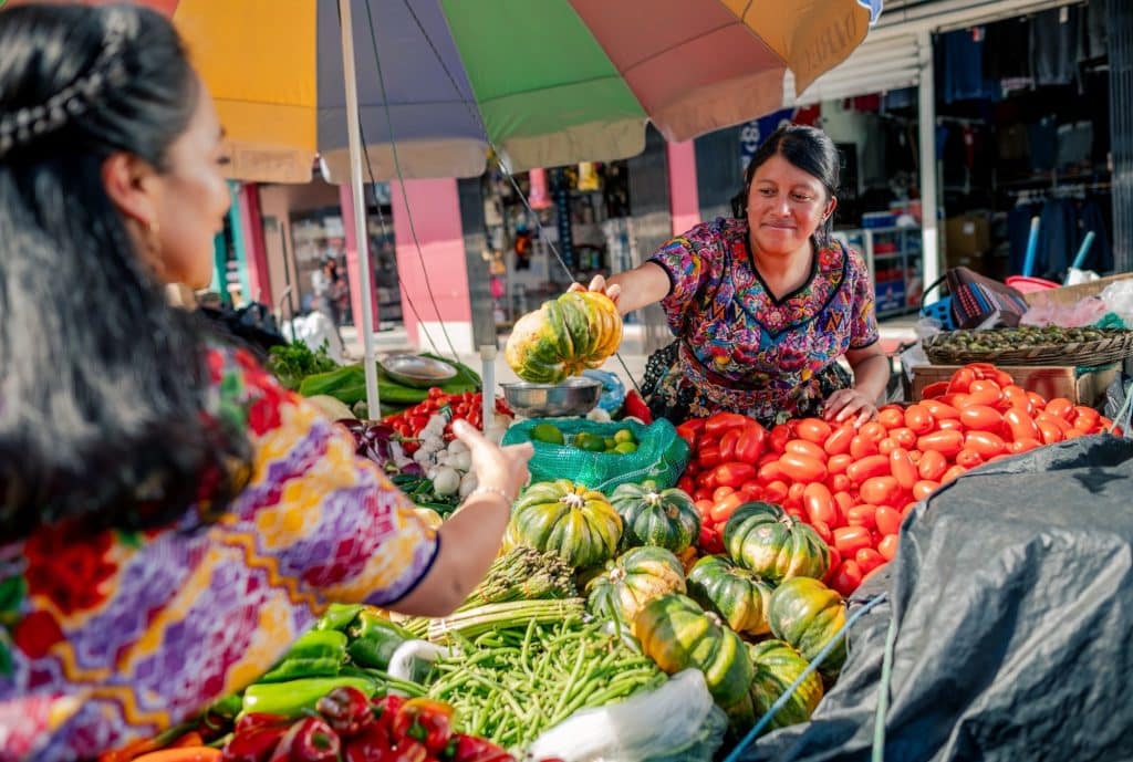 woman vendor handing tropical fruit.