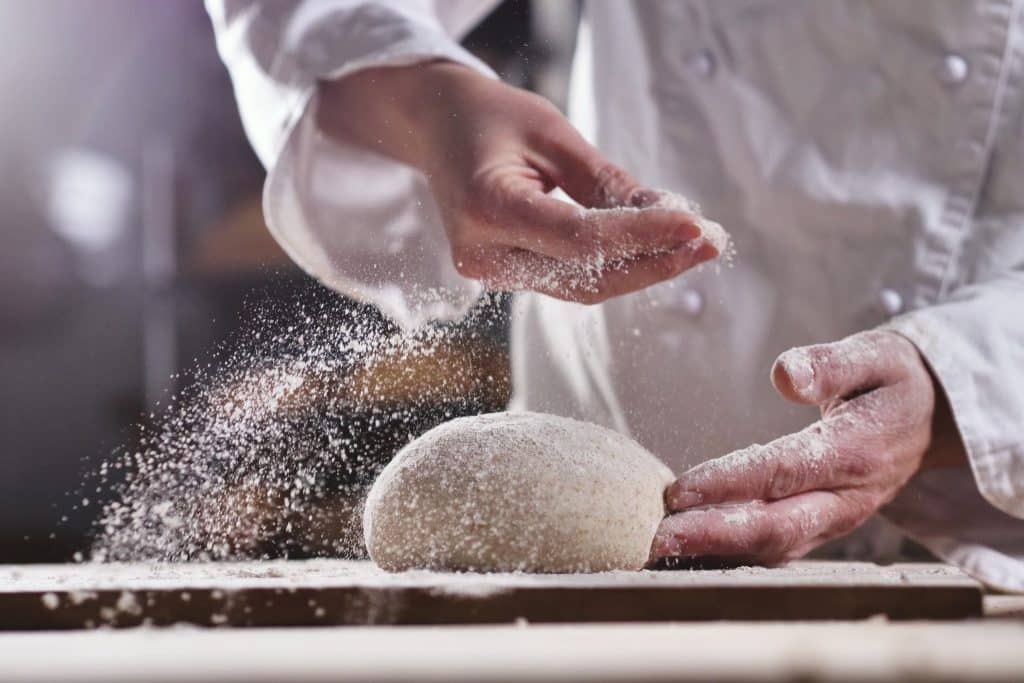 Baker dusting spent-grain flour, an upcycled food ingredients staple