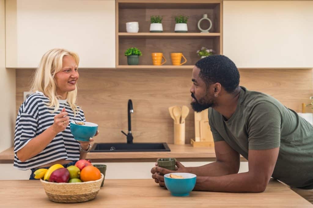 Happy couple eating oatmeal at a kitchen counter
