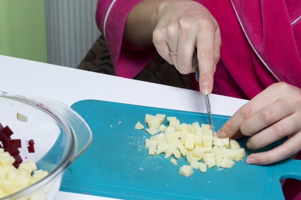 Hands dicing cooled potatoes for resistant starch salad