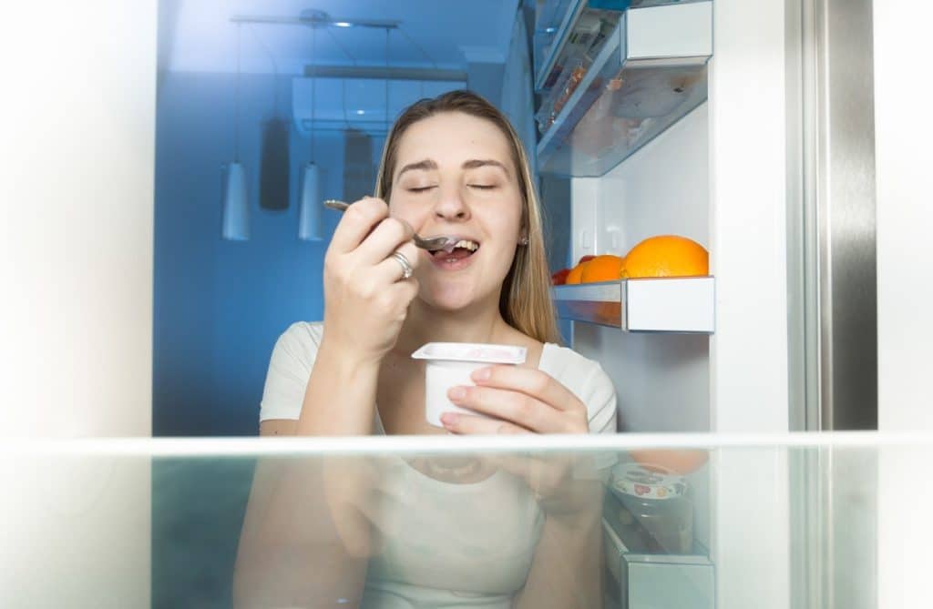 Woman enjoying yogurt with fruit as a smart snack for butyrate foods