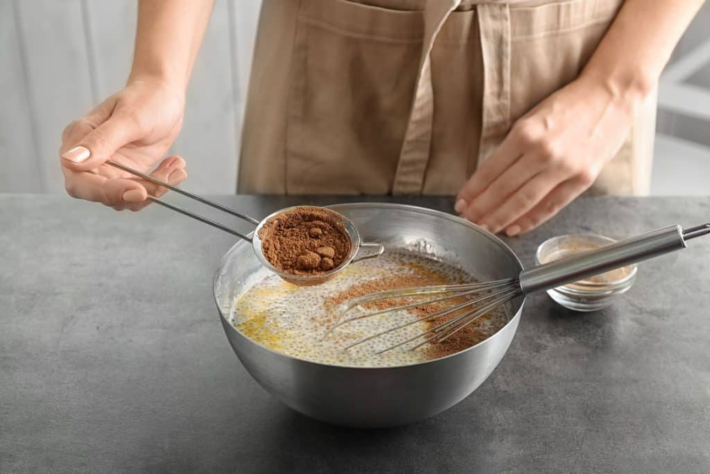 Hand adding superfood powder into a bowl with camu camu benefits