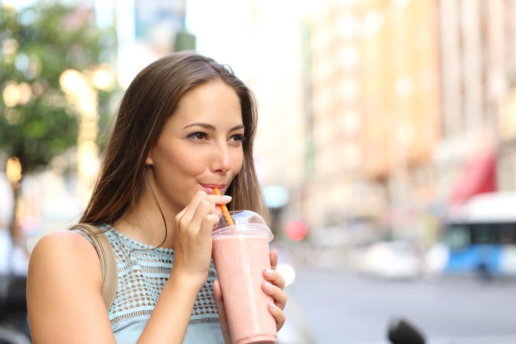 Woman drinking smoothie outdoors capturing daily camu camu benefits
