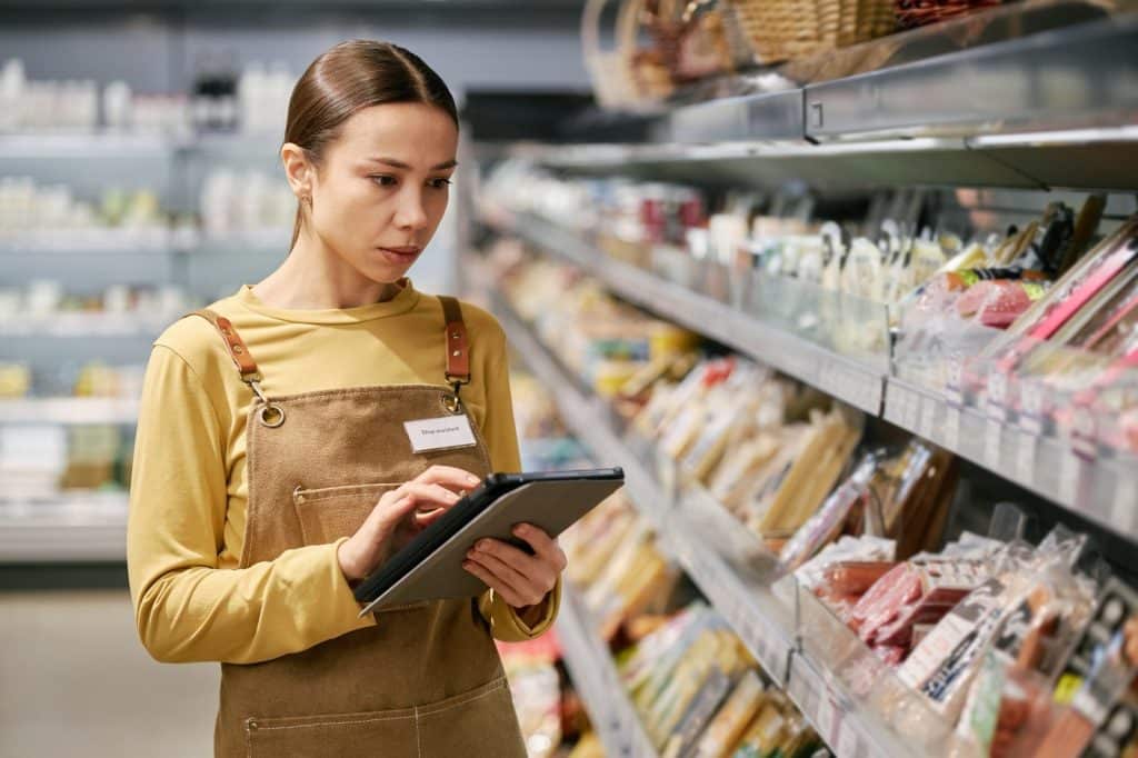 Grocery staff updates shelf tags and product data for label formats