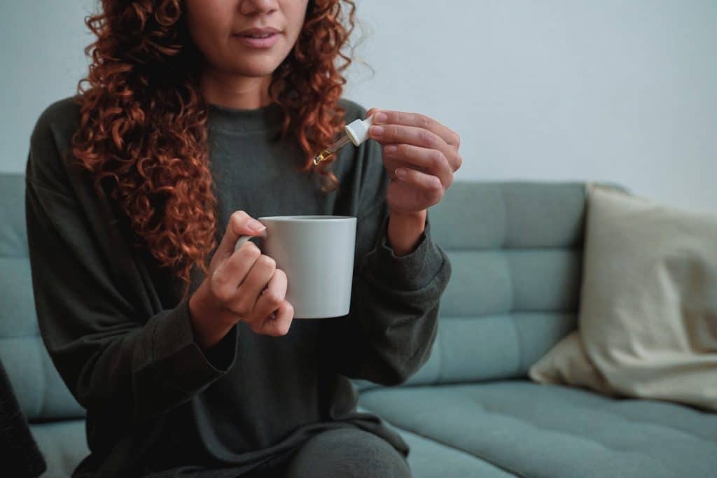 Person adding herbal drops into cup for digestive bitters benefits