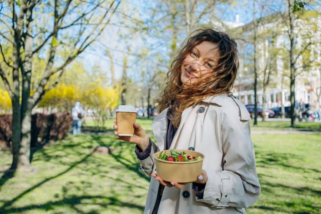 Smiling woman enjoying plain salad and black coffee connected to digestive bitters benefits