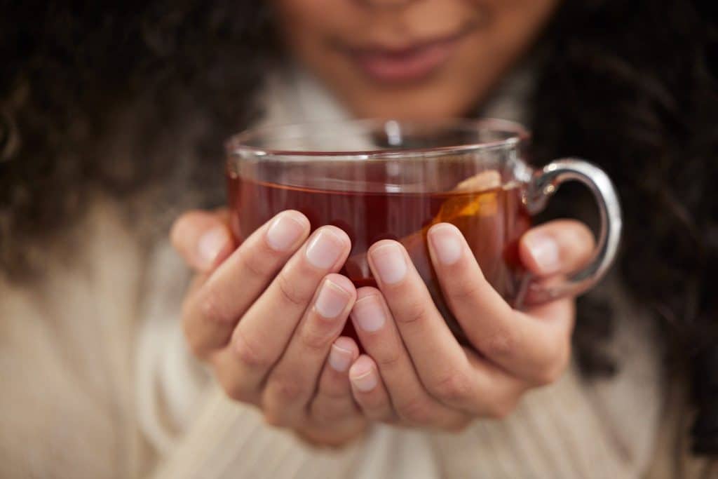Hands holding herbal tea cup showing digestive bitters benefits