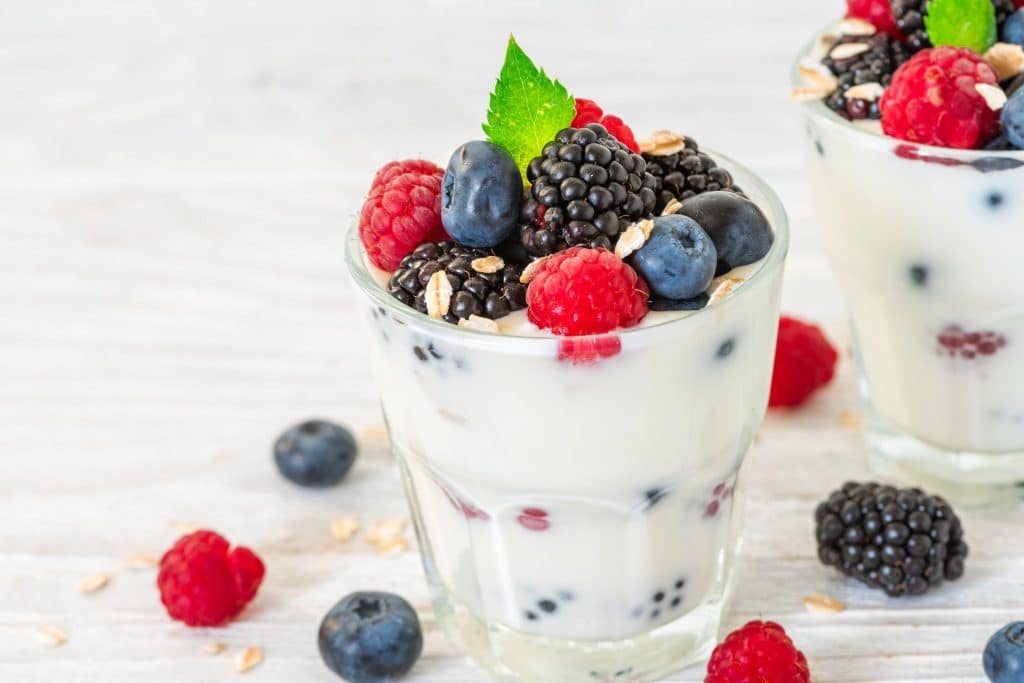 Yogurt with fresh berries in glass cup showing fermented foods microbiome diversity