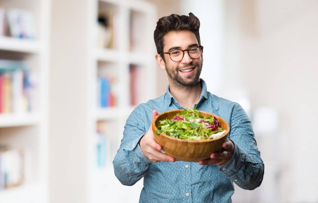 Happy young man holding a fresh salad.
