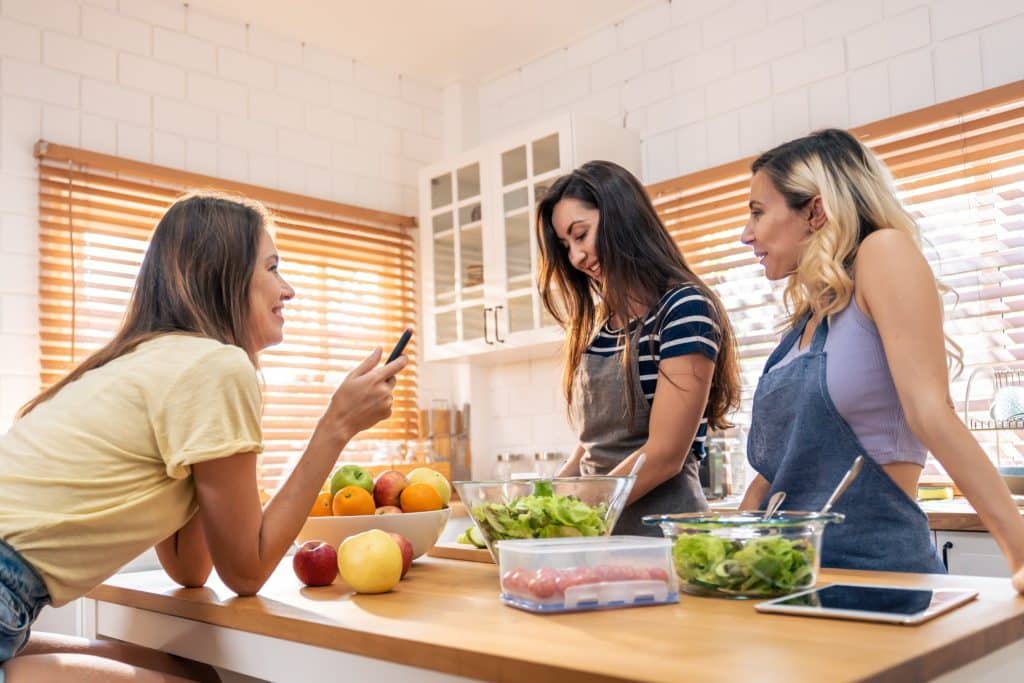 Friends preparing veggies, grains, and lean protein for an improve digestion diet.