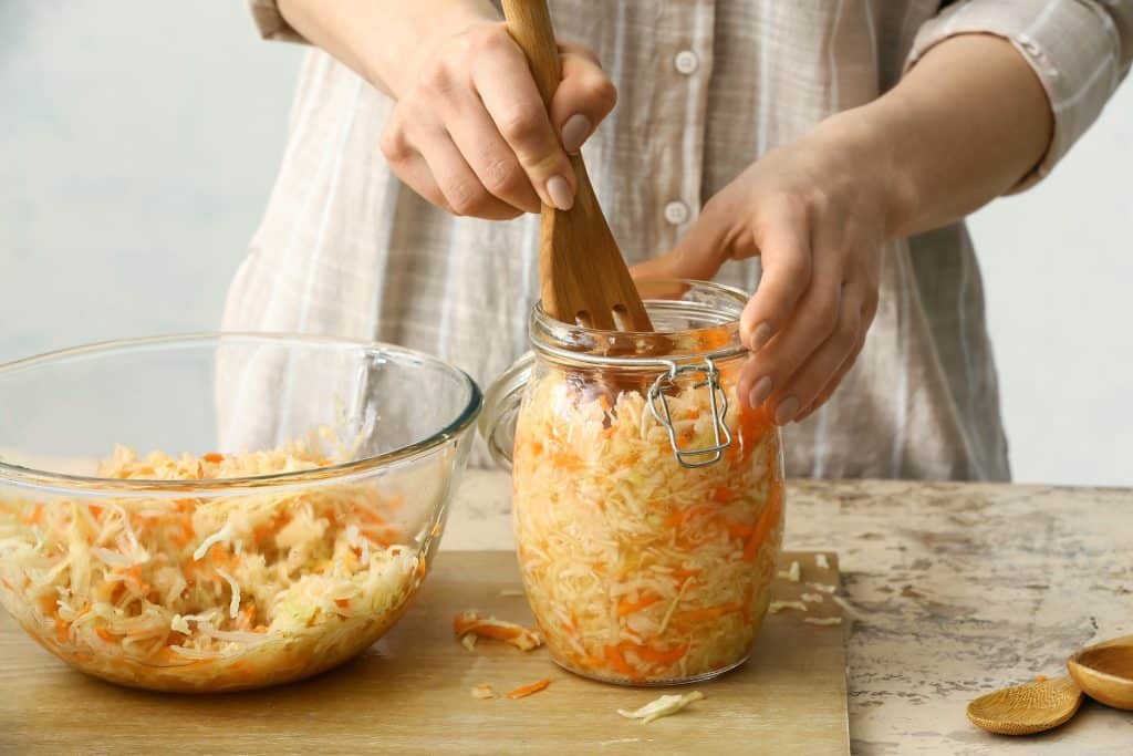 Packing homemade sauerkraut into a jar as part of an improve digestion diet.