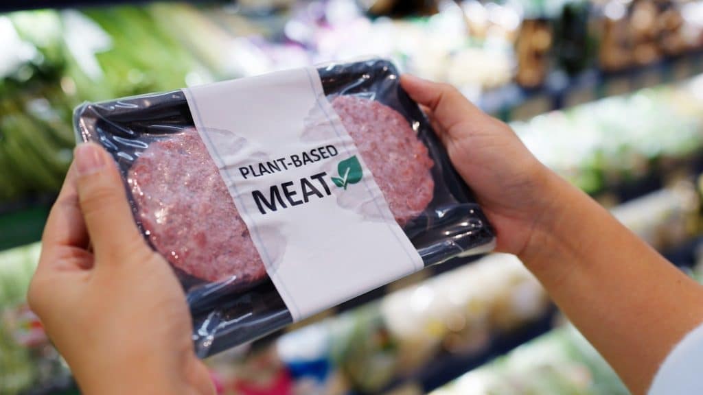 Customer comparing plant based and lab grown meat at store