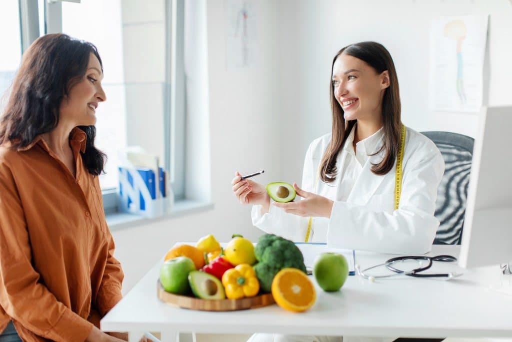 Nutritionist discussing low FODMAP foods with a client and fresh produce