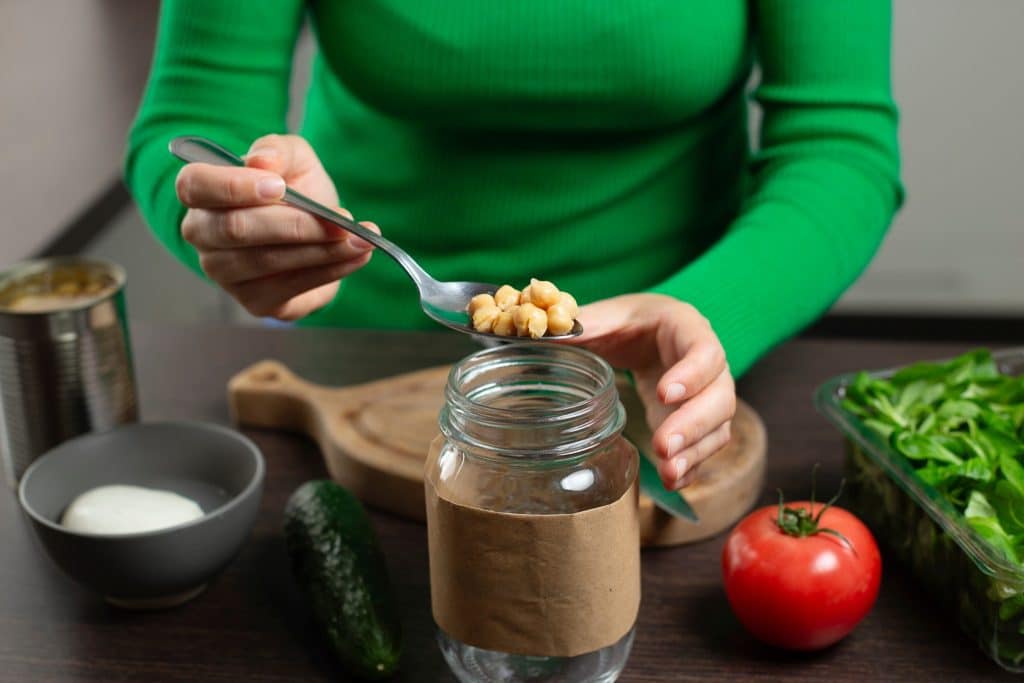 Woman meal-prepping chickpeas snack in jars
