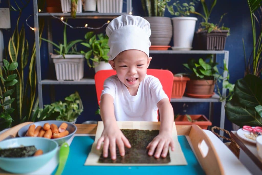 Smiling child preparing seaweed superfood rolls