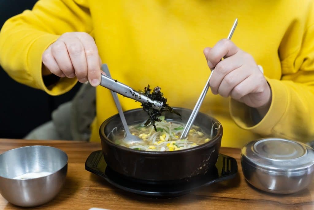 Person adding seaweed superfood to hot soup