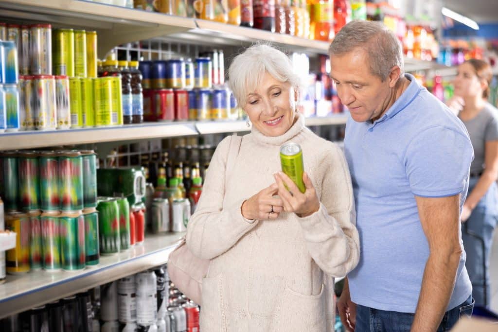 people checking beverage label in grocery store.