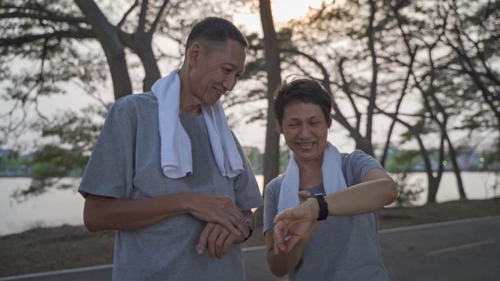 Active couple checking a fitness watch after a park walk