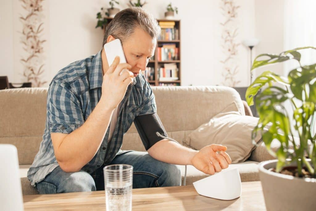 Man checking blood pressure at home while on the phone