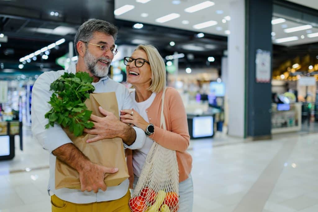 Shoppers carrying a paper grocery bag and reusable net tote—real-life choices that support sustainable packaging.