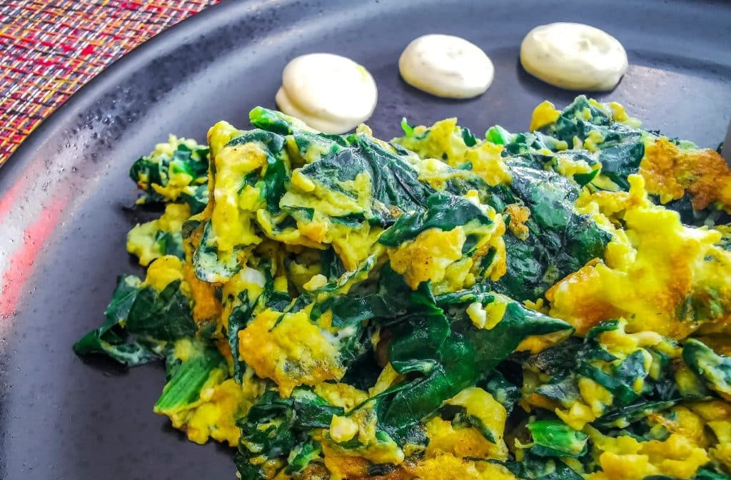Scrambled eggs with spinach on black plate supporting tryptophan foods mood