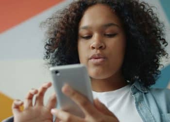 Young woman looking at her smartphone with colorful background.