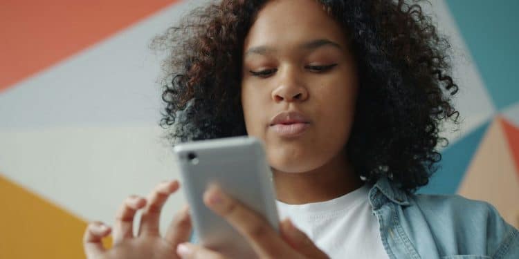 Young woman looking at her smartphone with colorful background.